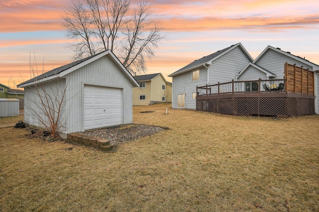 view of yard featuring a deck, driveway, a detached garage, and an outdoor structure