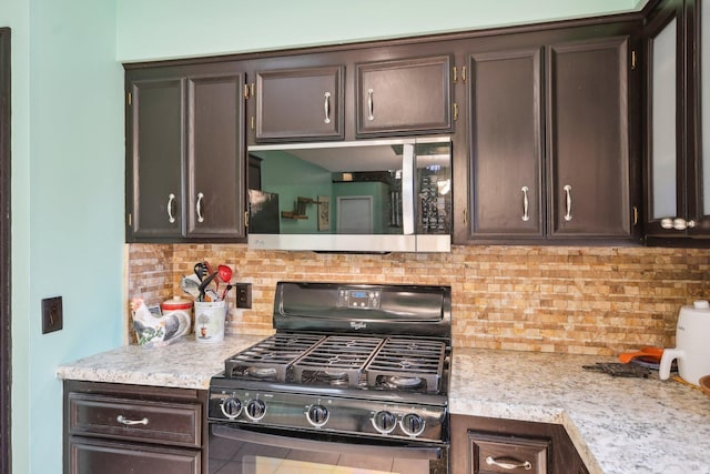 kitchen featuring light countertops, tasteful backsplash, stainless steel microwave, and black gas range oven