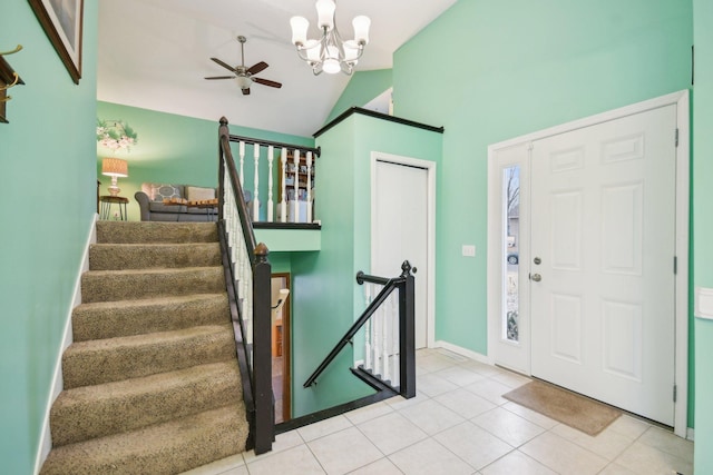 entrance foyer with ceiling fan with notable chandelier, baseboards, vaulted ceiling, stairs, and tile patterned floors