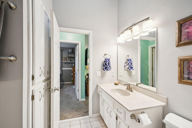 half bath featuring tile patterned flooring, baseboards, vanity, and toilet