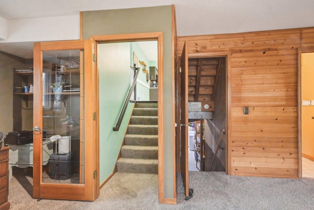 stairs featuring carpet and wooden walls