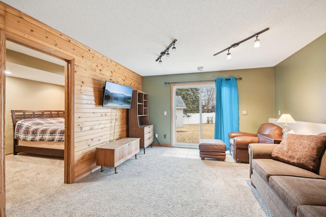 carpeted living room featuring a textured ceiling, track lighting, and wooden walls