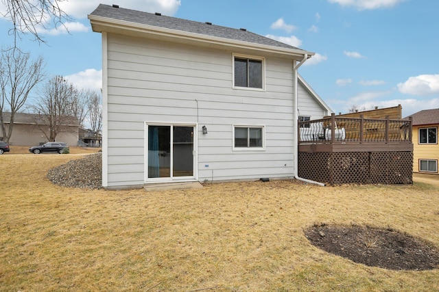 rear view of house featuring a wooden deck and a yard