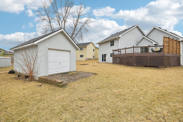 back of property with an outbuilding, a yard, a detached garage, a deck, and driveway