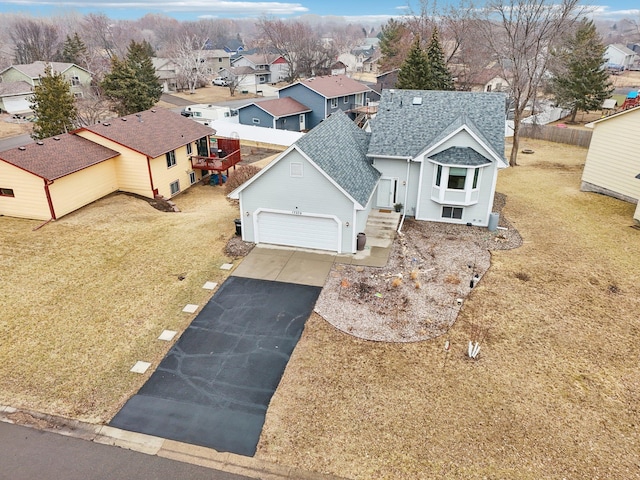 view of front of house with an attached garage, a shingled roof, fence, driveway, and a residential view