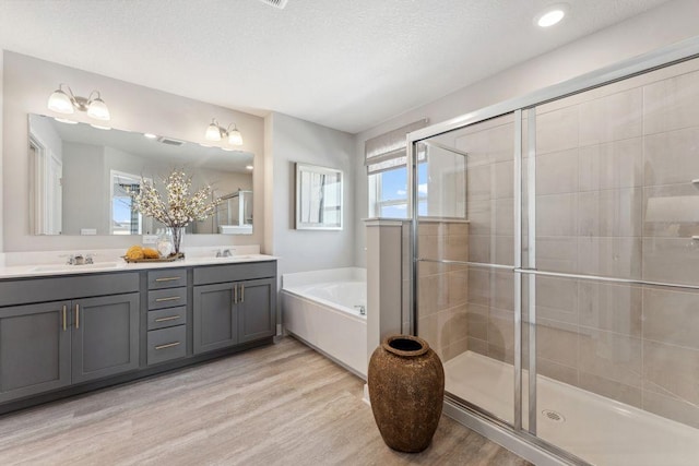 full bath featuring wood finished floors, a shower stall, a garden tub, and a textured ceiling