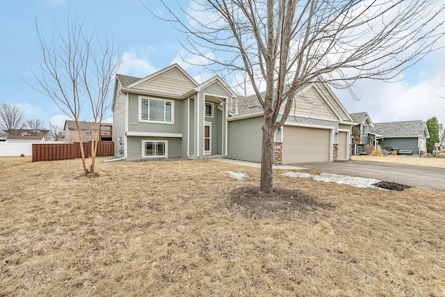 view of front of house featuring driveway, an attached garage, and fence