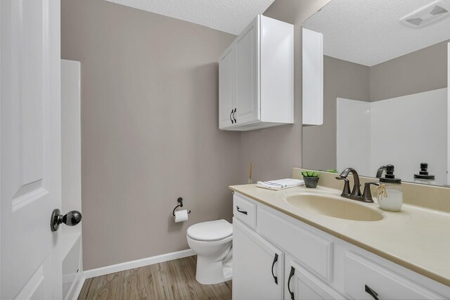 full bath featuring visible vents, toilet, vanity, a textured ceiling, and wood finished floors