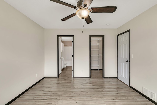 unfurnished bedroom featuring light wood-type flooring, a closet, visible vents, and a spacious closet