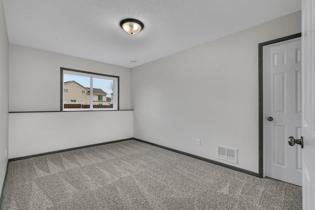 unfurnished room featuring carpet, a textured ceiling, visible vents, and baseboards