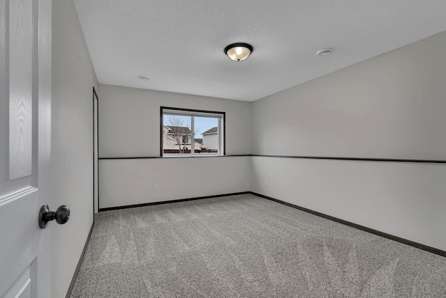 carpeted empty room featuring a textured ceiling and baseboards