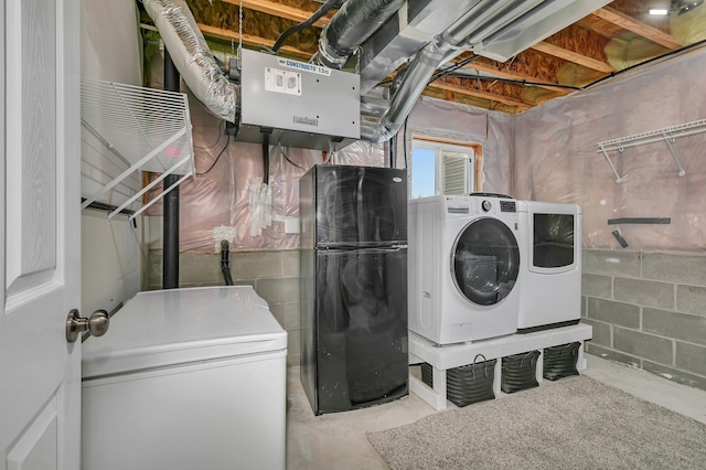 laundry area featuring laundry area, washing machine and clothes dryer, and concrete block wall