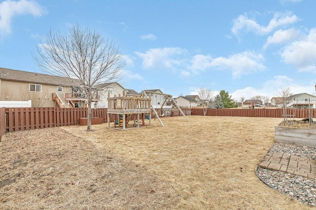 view of yard featuring a playground, a fenced backyard, and a residential view