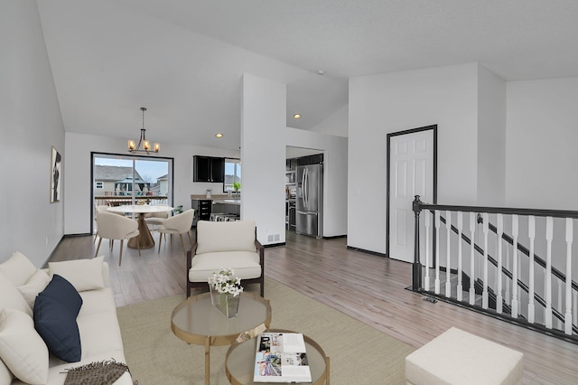 living room with recessed lighting, high vaulted ceiling, a notable chandelier, and wood finished floors