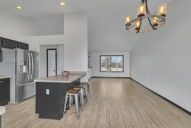 kitchen with a peninsula, light wood finished floors, stainless steel refrigerator with ice dispenser, and a kitchen breakfast bar