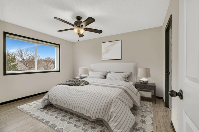 bedroom featuring ceiling fan, light wood-type flooring, and baseboards