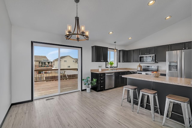 kitchen with appliances with stainless steel finishes, a breakfast bar, light countertops, and dark cabinetry