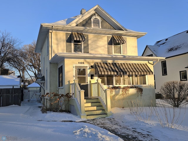 view of front of house with a chimney, fence, and stucco siding