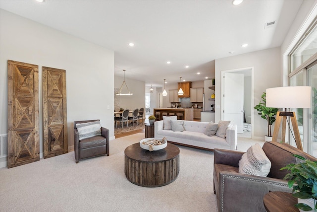 living area with light carpet, visible vents, and recessed lighting