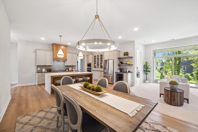 dining space featuring light wood-type flooring, an inviting chandelier, baseboards, wine cooler, and recessed lighting