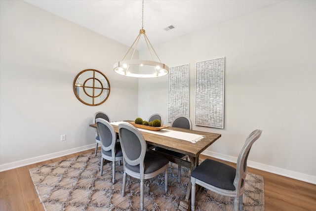 dining area featuring visible vents, wood finished floors, baseboards, and a chandelier
