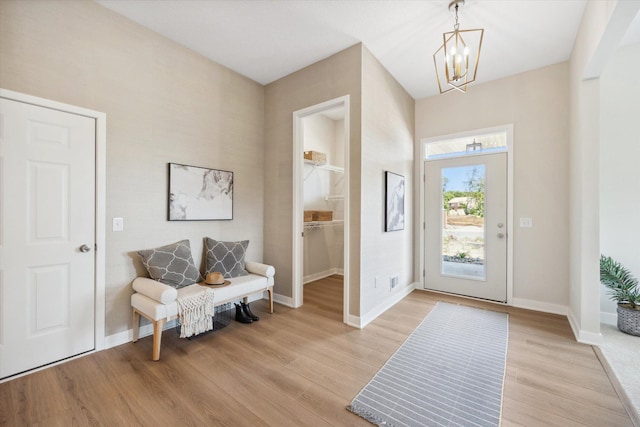 foyer entrance featuring a notable chandelier, baseboards, and light wood-style floors