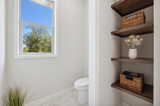 bathroom with marble finish floor, baseboards, and toilet