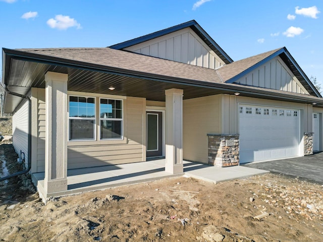 view of front facade with a garage, a shingled roof, and board and batten siding