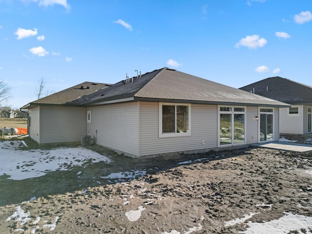 rear view of house with a patio area, a shingled roof, and central AC