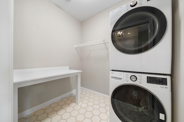 washroom with baseboards, laundry area, a textured ceiling, and stacked washer / drying machine