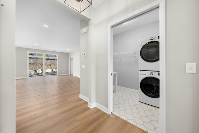 laundry room featuring laundry area, baseboards, light wood-style floors, stacked washing maching and dryer, and recessed lighting