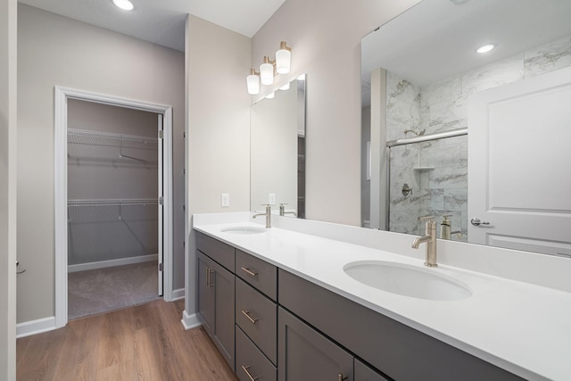 full bath with a stall shower, a sink, a spacious closet, and wood finished floors