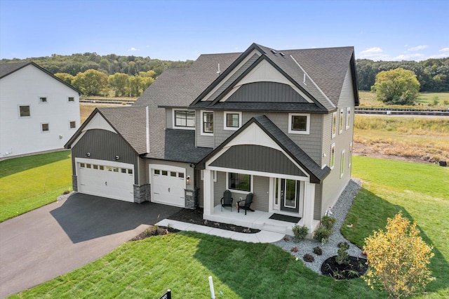 view of front of home featuring driveway, a front lawn, roof with shingles, and a porch