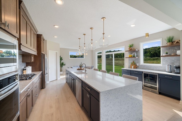 kitchen featuring stainless steel appliances, wine cooler, a sink, and open shelves