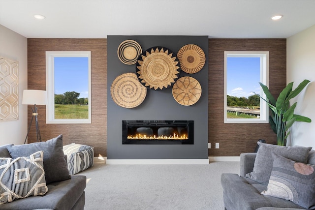 carpeted living room featuring recessed lighting, an accent wall, baseboards, and a glass covered fireplace