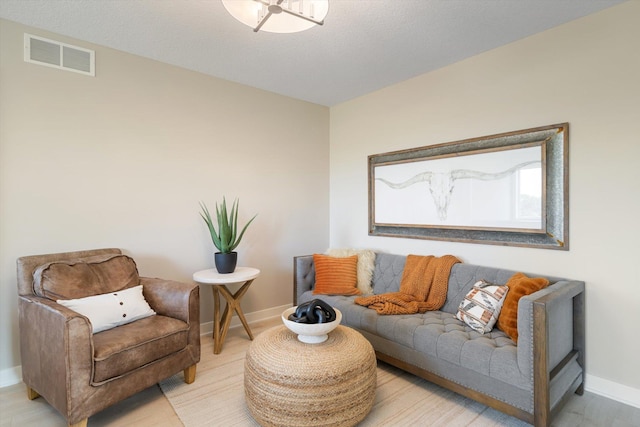 living room with light wood-style floors, baseboards, and visible vents