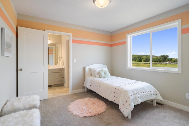 bedroom featuring light carpet, baseboards, and ensuite bathroom