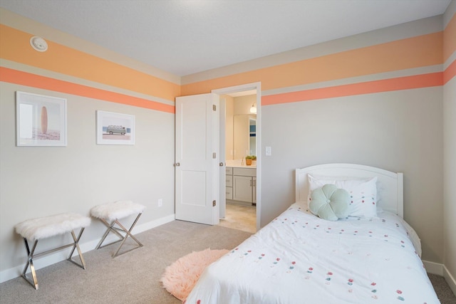 bedroom with light carpet, ensuite bathroom, and baseboards