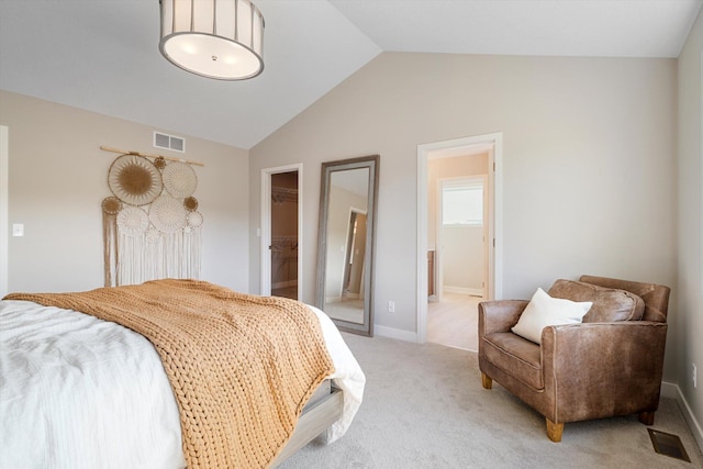 bedroom with a walk in closet, visible vents, vaulted ceiling, and light colored carpet