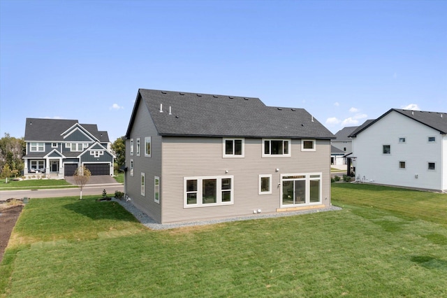 rear view of property featuring roof with shingles and a yard