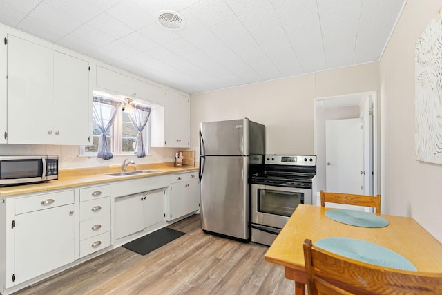 kitchen with visible vents, light wood-type flooring, light countertops, a sink, and appliances with stainless steel finishes