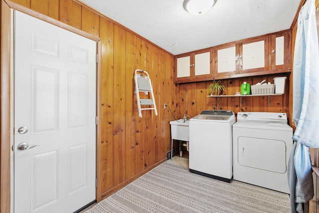 washroom with wooden walls, laundry area, light carpet, a sink, and washer and clothes dryer
