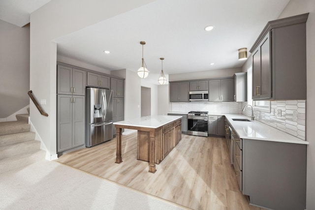 kitchen with a center island, a sink, gray cabinets, stainless steel appliances, and backsplash