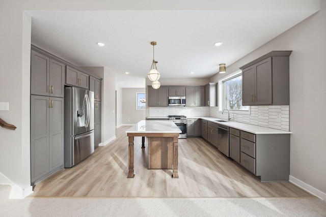 kitchen with stainless steel appliances, light countertops, a kitchen island, and decorative backsplash