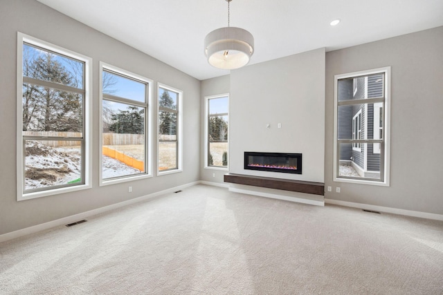 unfurnished living room featuring carpet floors, visible vents, and baseboards