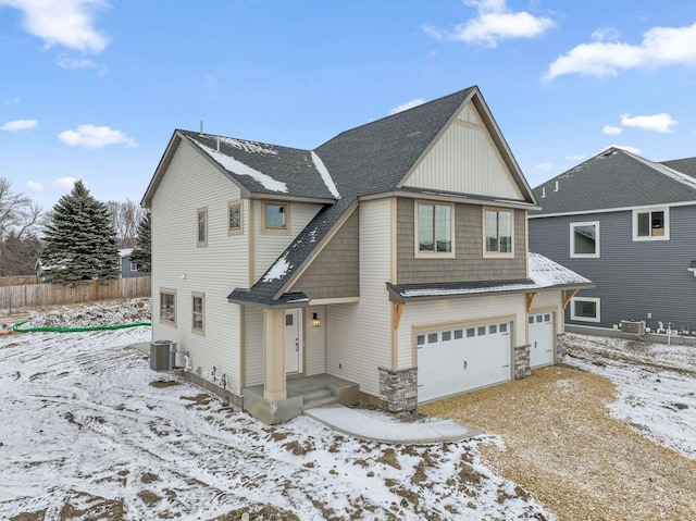 view of front of home featuring a garage, stone siding, fence, and central AC unit