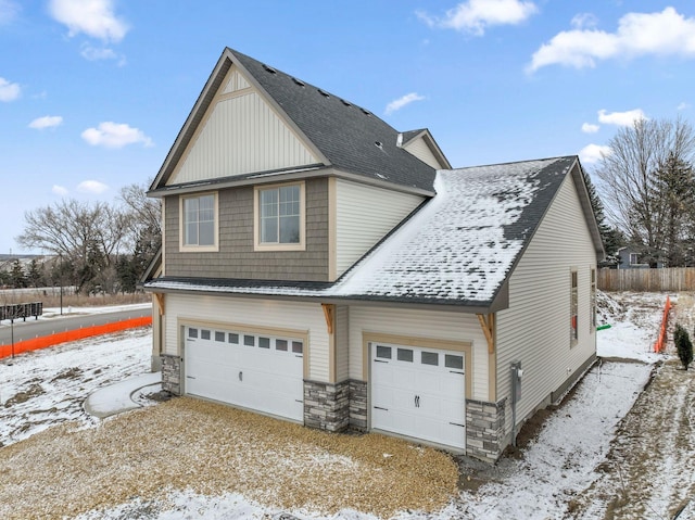 exterior space featuring stone siding, roof with shingles, fence, and driveway