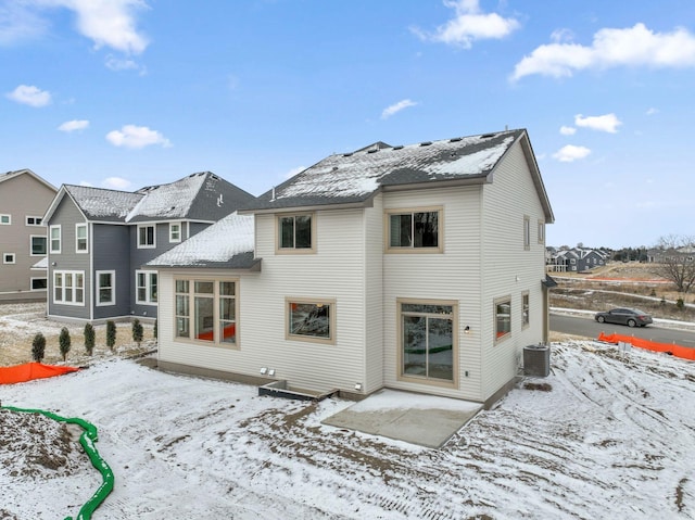 snow covered property featuring central AC unit and a patio