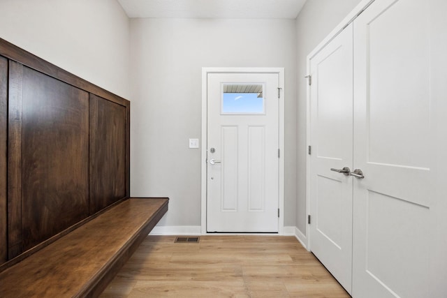 foyer featuring light wood-type flooring, baseboards, and visible vents