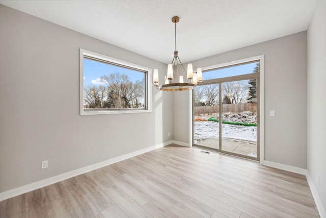 interior space featuring light wood finished floors, visible vents, an inviting chandelier, a textured ceiling, and baseboards